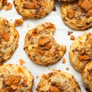 Butterfinger Cookies on a white table with the center cookie having a bite taken out of it.