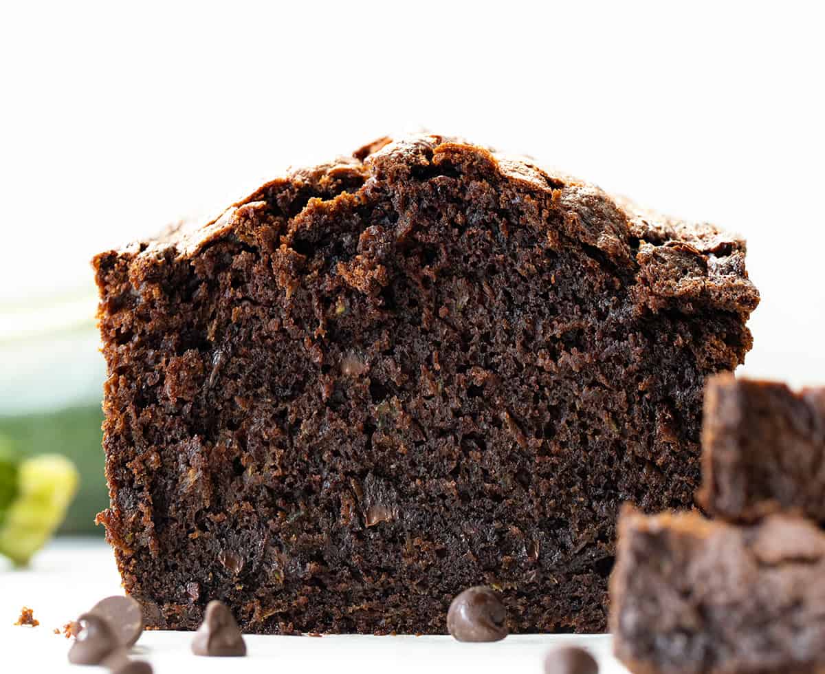 This Chocolate Zucchini Bread is rich, moist, and loaded with melty chocolate chips! Proof that veggies and dessert really can be best friends. With deep cocoa flavor, a perfectly tender crumb, and just the right amount of sweetness, you’d never guess there’s zucchini hiding inside! CLose up of Chocolate Zucchini Bread loaf with piece cut off.