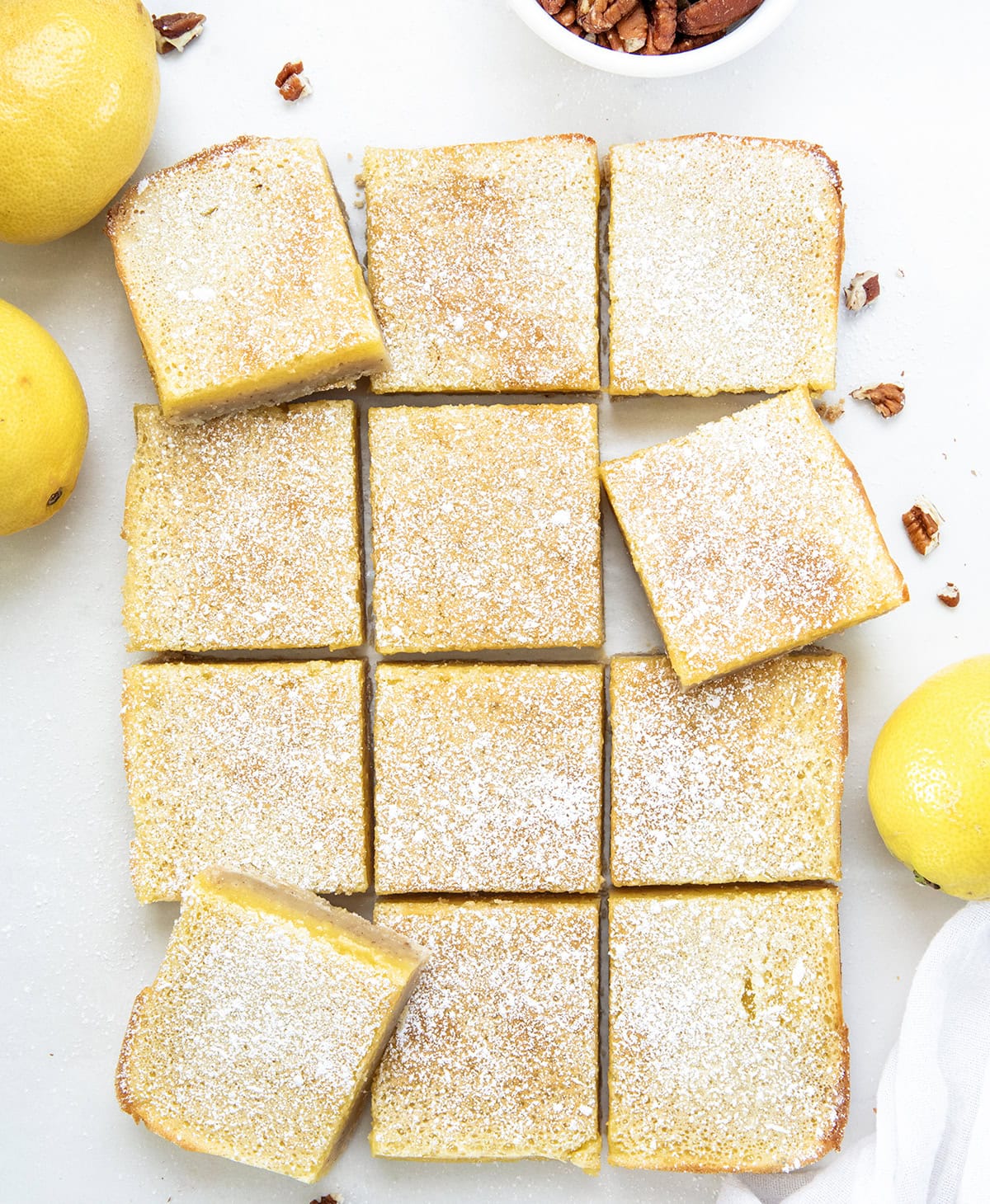 If you have made my (dare I say perfect) Lemon Bars, you already know how bright, tangy, and smooth that lemon filling is. This time, I am changing up the base with a toasted pecan crust. The buttery shortbread takes on a nutty richness, adding extra flavor and a soft crunch that pairs so well with the fresh lemon layer! Lemon Bars with Pecan Crust cut into squares on a white table from overhead.