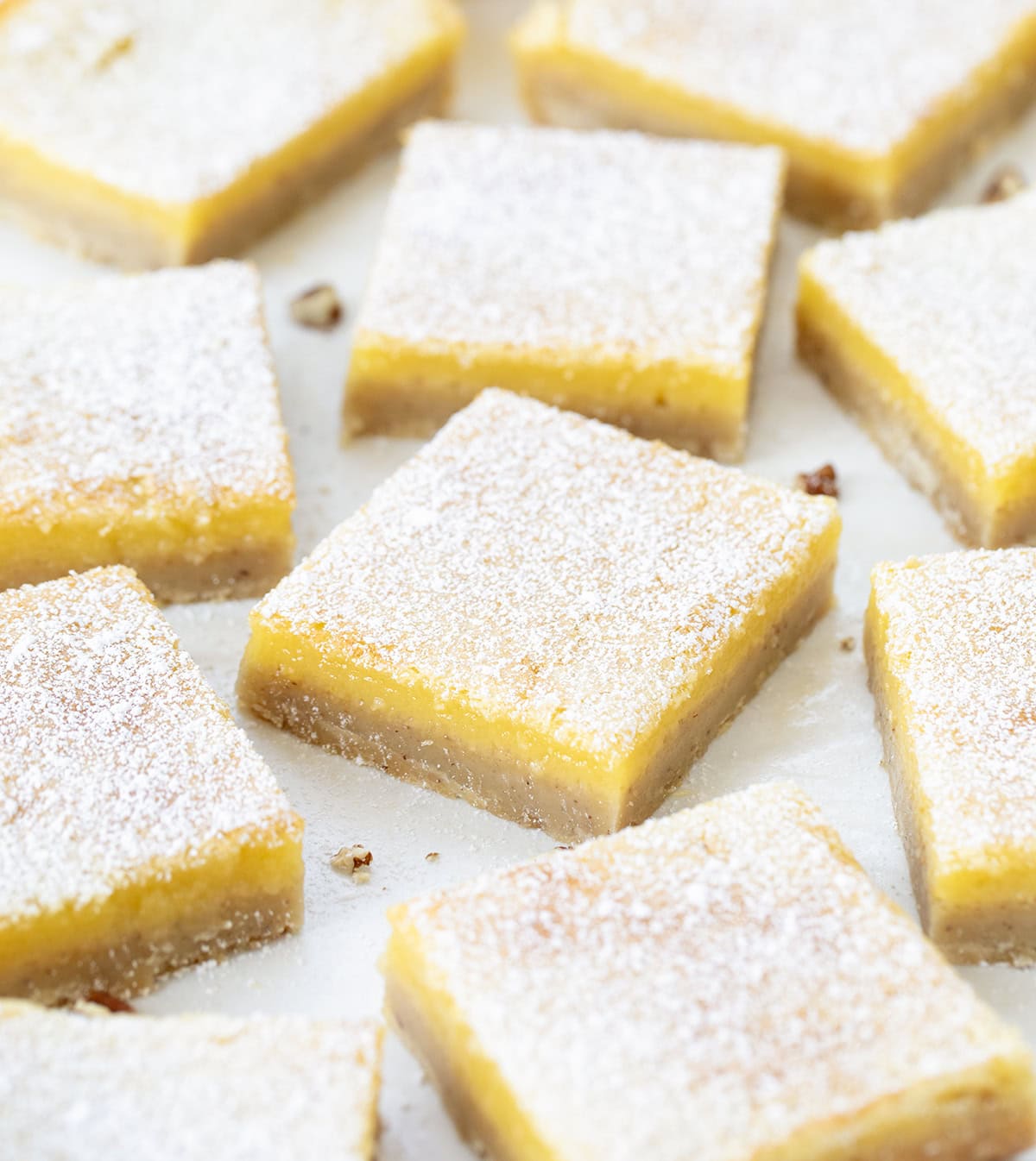 If you have made my (dare I say perfect) Lemon Bars, you already know how bright, tangy, and smooth that lemon filling is. This time, I am changing up the base with a toasted pecan crust. The buttery shortbread takes on a nutty richness, adding extra flavor and a soft crunch that pairs so well with the fresh lemon layer! Lemon Bars with Pecan Crust cut into squares on a white table close up.
