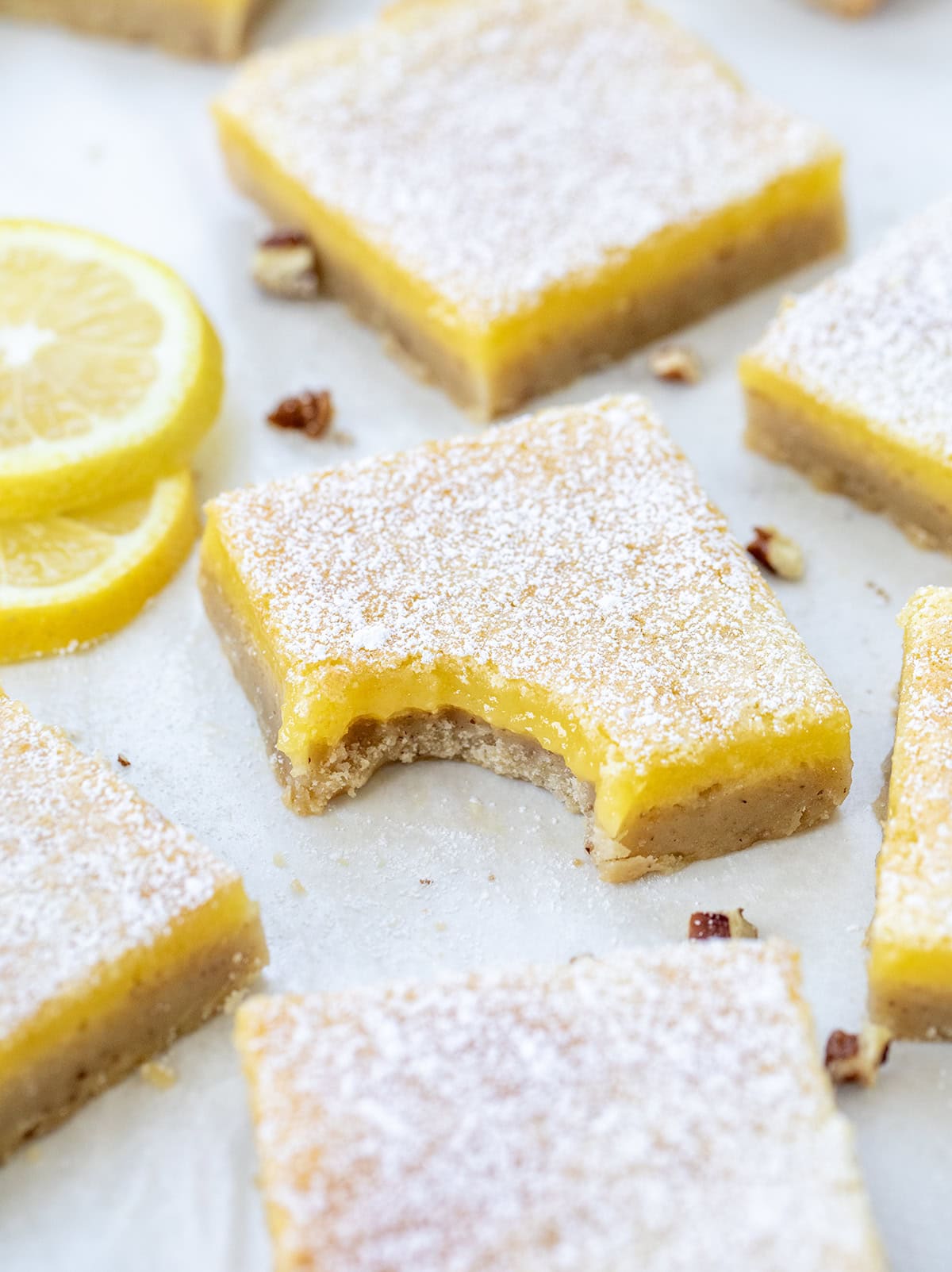 If you have made my (dare I say perfect) Lemon Bars, you already know how bright, tangy, and smooth that lemon filling is. This time, I am changing up the base with a toasted pecan crust. The buttery shortbread takes on a nutty richness, adding extra flavor and a soft crunch that pairs so well with the fresh lemon layer! Lemon Bars with Pecan Crust cut into squares with center bar having a bite taken out of it.