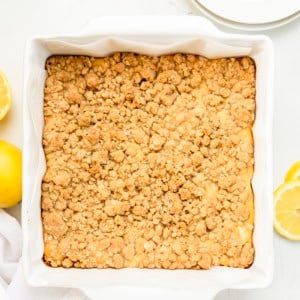 White pan of Lemonade Crumb Bars on a white table with fresh lemon from overhead.