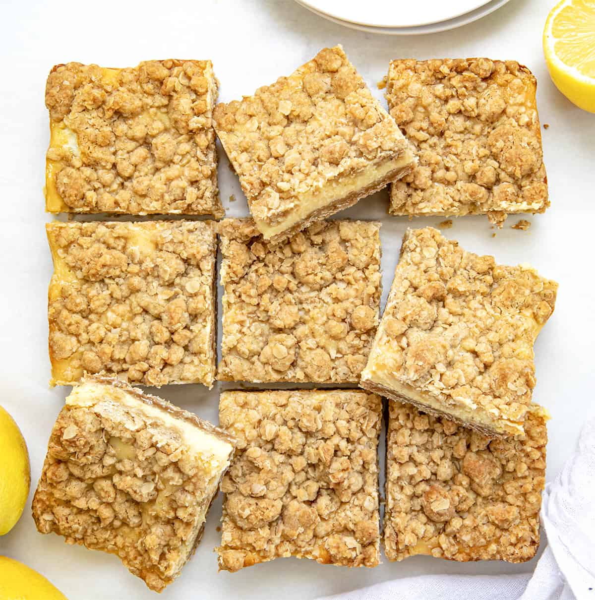 If you love my Lemon Crumb Bars, youโre going to love this fun variation! These Lemonade Crumb Bars use frozen lemonade concentrate for an extra punch of bright, tangy flavor. Theyโre simple to make, with a creamy lemon filling and a soft, crumbly oat crust and topping. Great for summer or anytime youโre craving something sweet and citrusy. Lemonade Crumb Bars cut into squares and some askew from overhead.