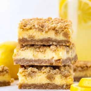 Stack of Lemonade Crumb Bars with a pitcher of lemonade in the background.