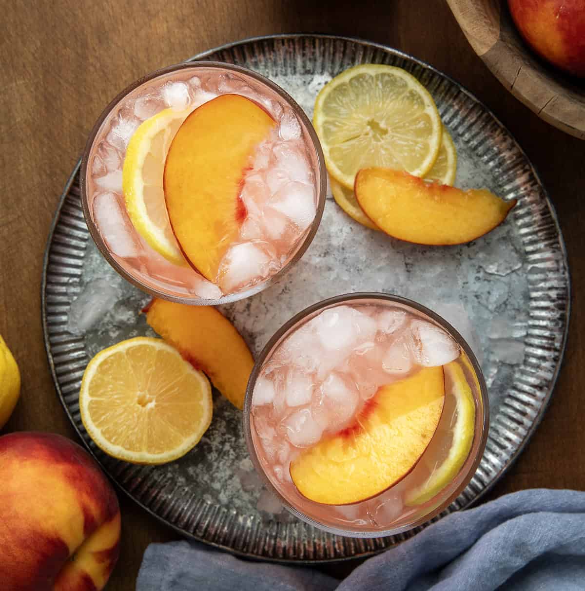 Two glasses of Peach Lemonade on a tray on a wooden table from overhead.
