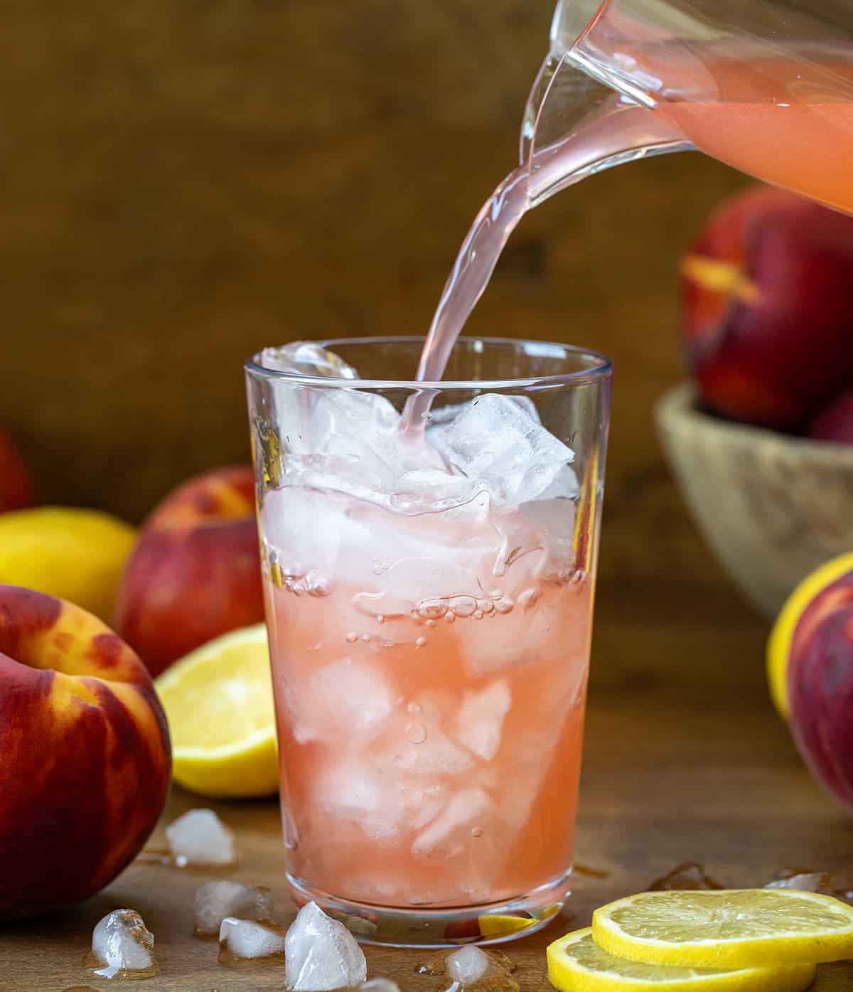 Pouring Peach Lemonade into a glass from a pitcher.