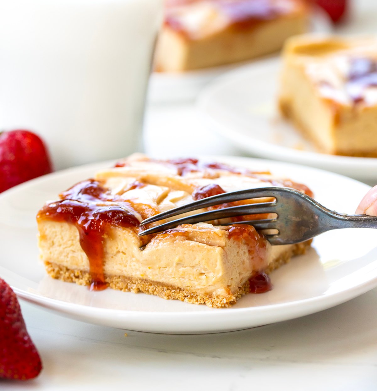 Fork taking a bite from a slice of Peanut Butter and Jelly Cheesecake.