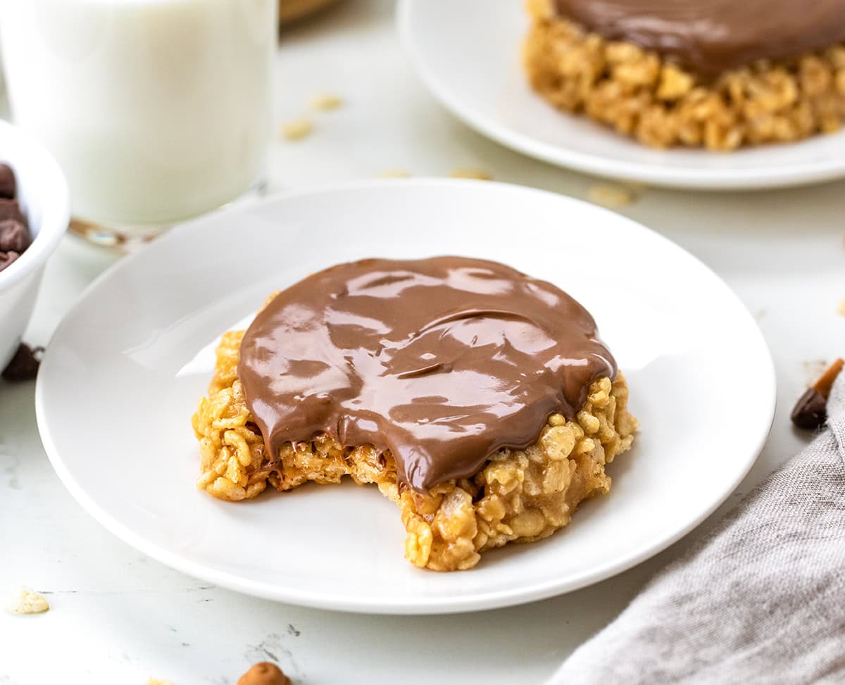 This One-Minute Scotcheroo (made in a mug) is my go-to when I’m craving something sweet and quick, just for me! All the classic Scotcheroo flavor, shaped like a cookie, no oven needed! Single-Serving Scotcheroo made in a mug on a white plate with a bite taken out of it.