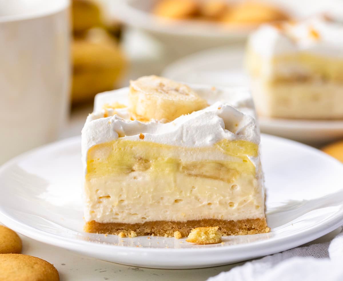 These Banana Cream Bars are an easy summer dessert that everyone will love! The no-bake dessert has a vanilla wafer crust, creamy filling, fresh bananas, and fluffy topping. Itโs cool, creamy, and perfect for hot days when you donโt want to turn on the oven. Banana Cream Pie Bar on a white plate.