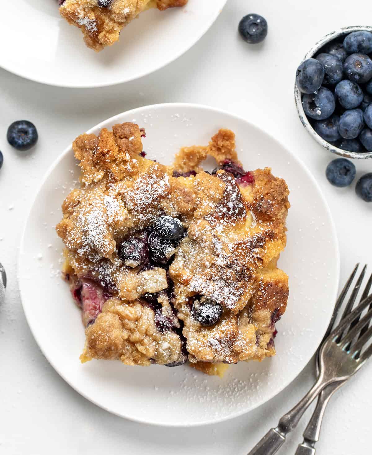 Blueberry Lemon French Toast on a white plate on a white table from overhead.