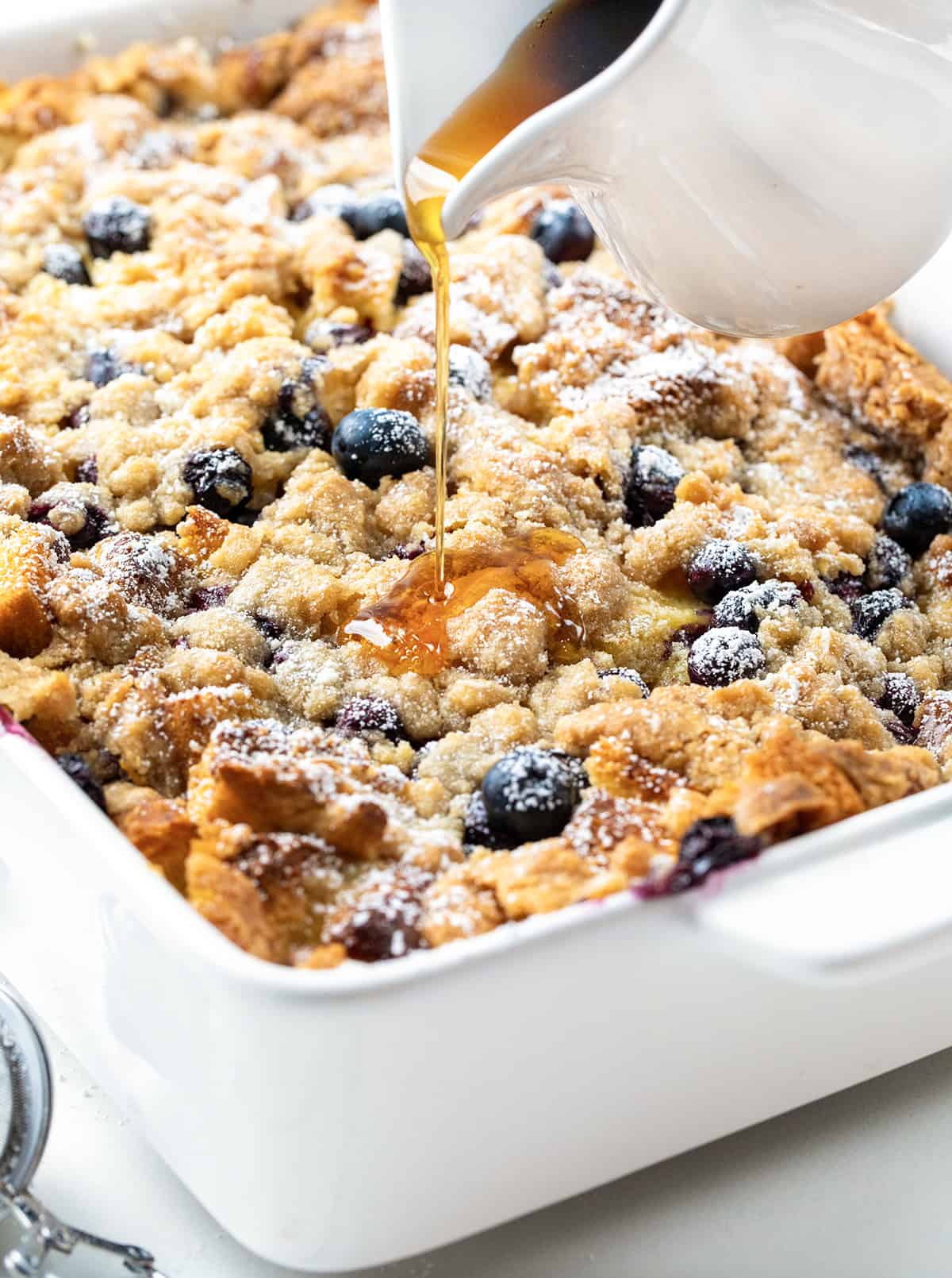 Pouring syrup over Blueberry Lemon French Toast Bake.