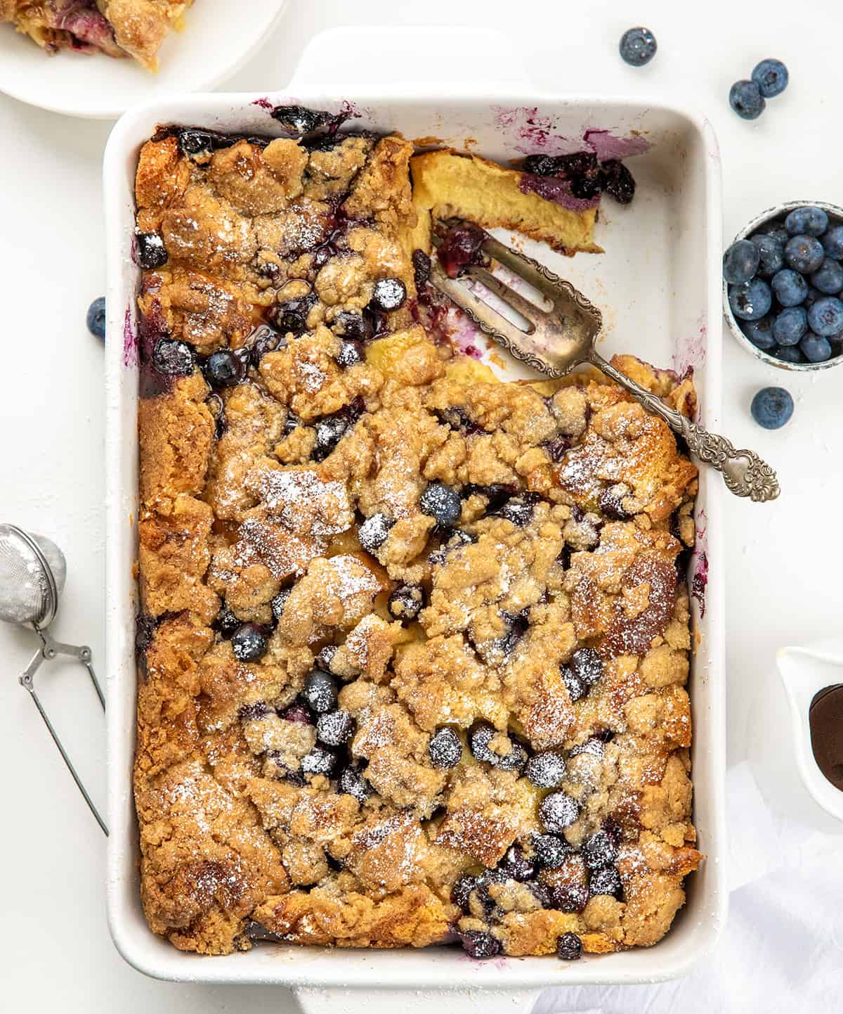 Blueberry Lemon French Toast Bake in a white casserole dish with a small portion removed from overhead. 