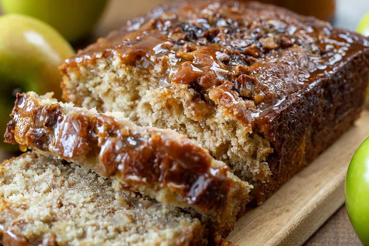 Caramel Apple Fritter Bread takes my fan-favorite Apple Fritter Bread and layers in a sweet caramel drizzle for the ultimate fall baking treat. Soft and tender with cinnamon-sugar apples swirled throughout, this bread is like biting into a caramel apple fritter, with no frying required! Close up of cut pieces of Caramel Apple Fritter Bread showing tender texture.