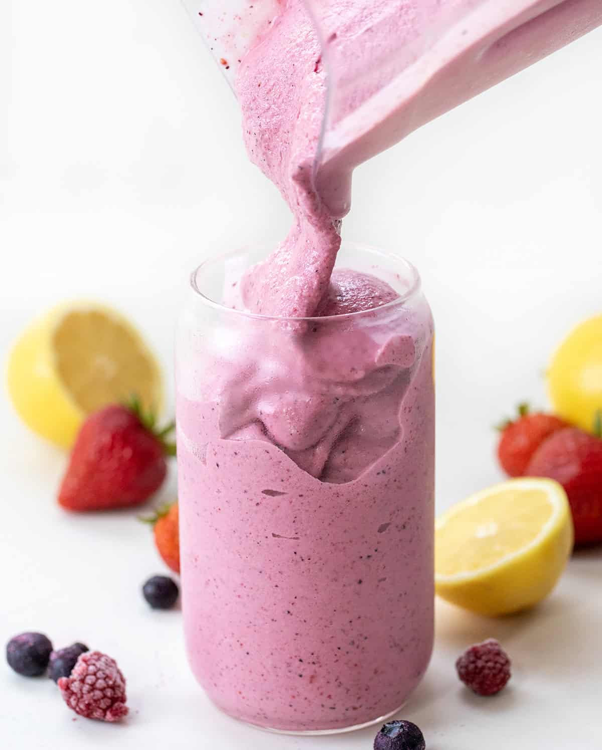 Pouring Frosted Mixed Berry Lemonade into a chilled glass.