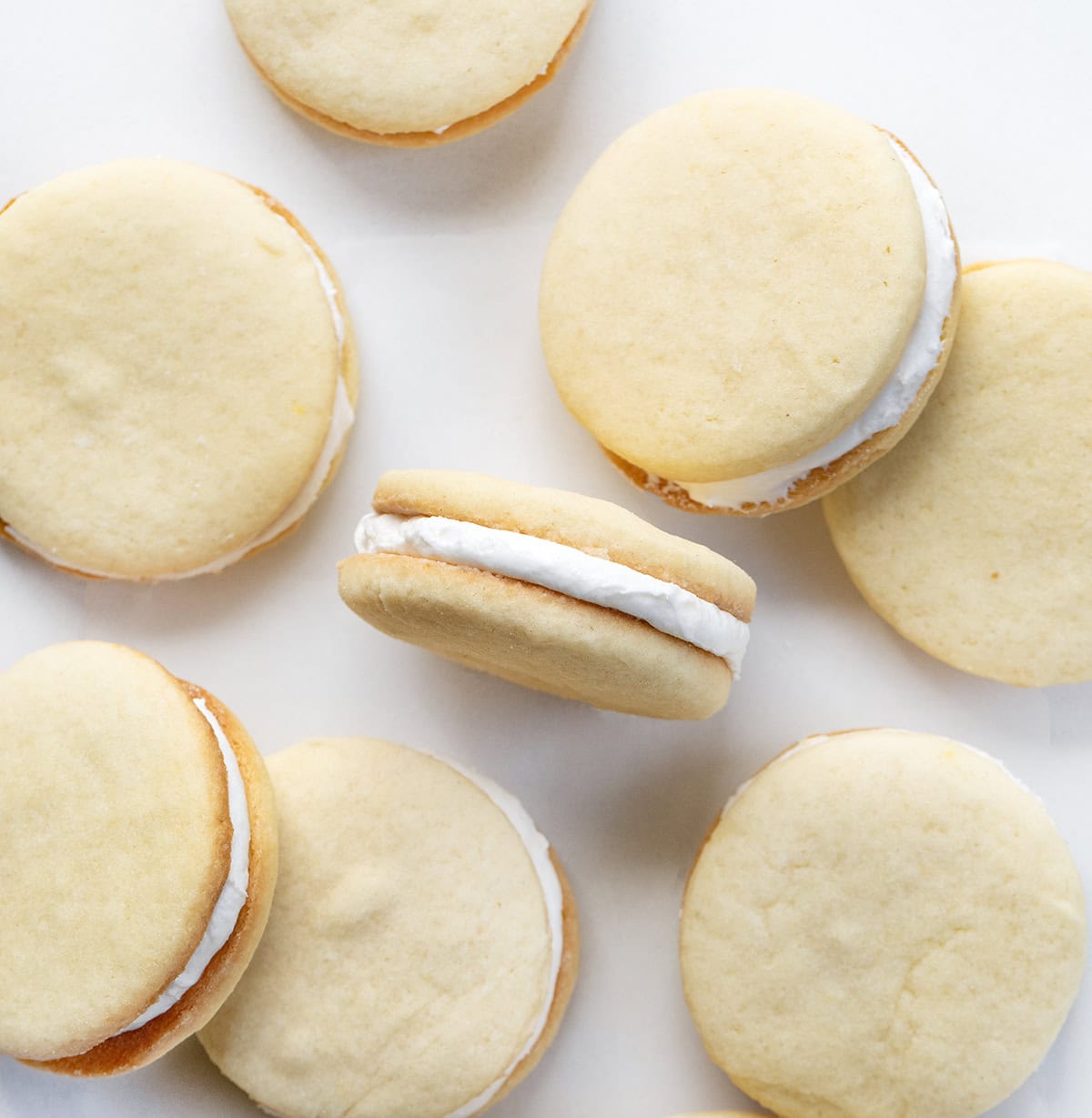 If you love Golden Oreos, you have to try these homemade Golden Oreo cookies! Theyโre soft, buttery sandwich cookies filled with my creamy marshmallow buttercream for the perfect sweet bite! Homemade Golden Oreo Cookies on a white table from overhead.