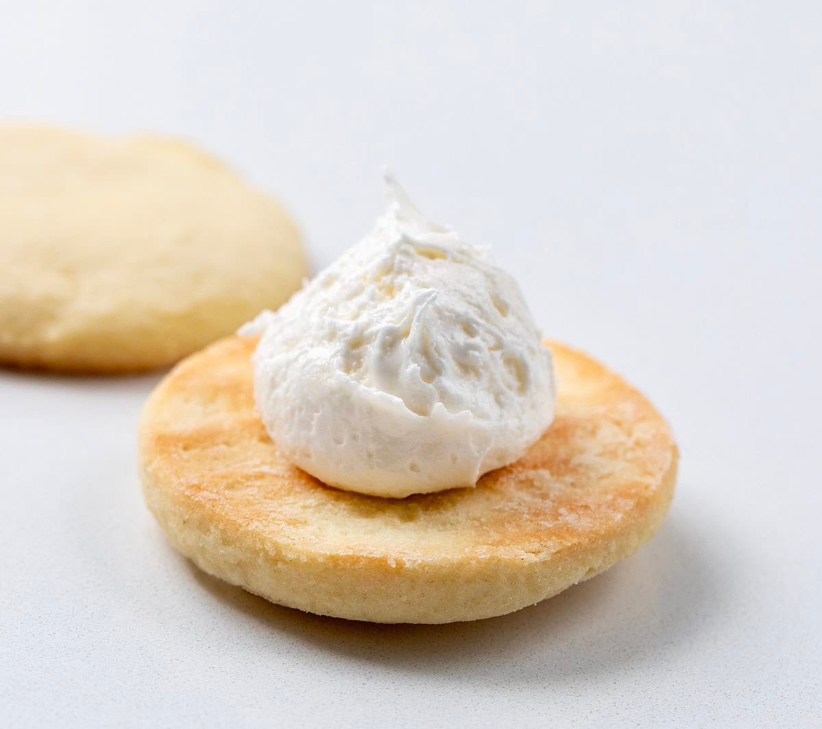 If you love Golden Oreos, you have to try these homemade Golden Oreo cookies! Theyโre soft, buttery sandwich cookies filled with my creamy marshmallow buttercream for the perfect sweet bite! Adding frosting to one homemade golden oreo cookie before making it a sandwich.