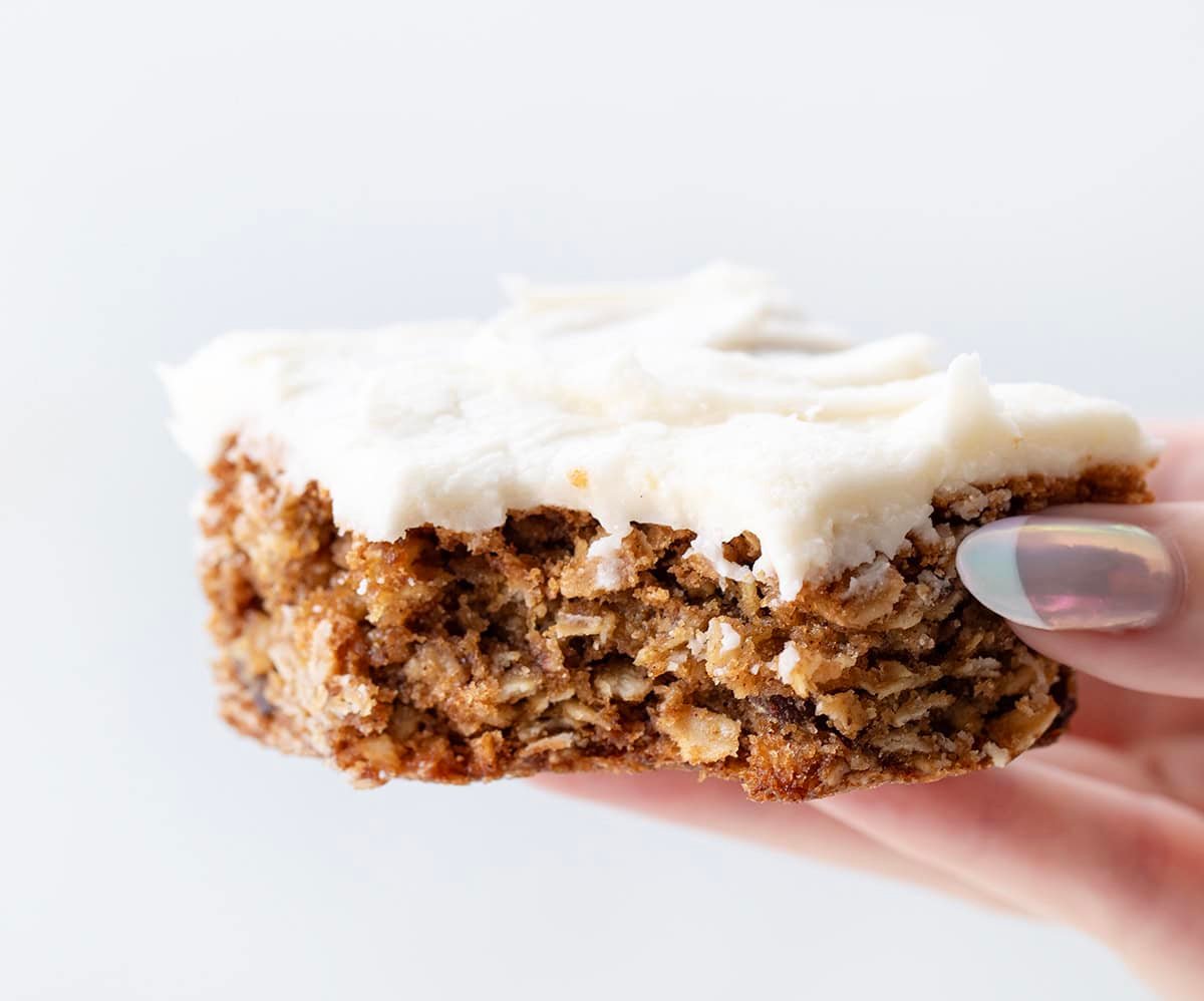 Hand holding a Oatmeal Raisin Cookie Bar that has a bite taken out.