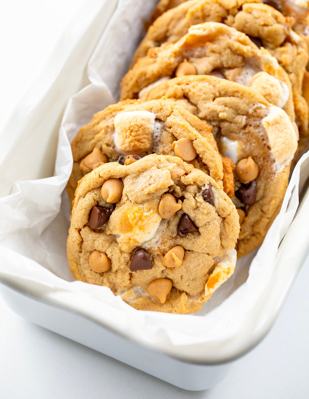 Soft, chewy peanut butter marshmallow cookies loaded with melty chocolate chips and gooey marshmallows. Easy, delicious, and perfect for any cookie lover! Peanut Butter Marshmallow Cookies on a white dish close up.