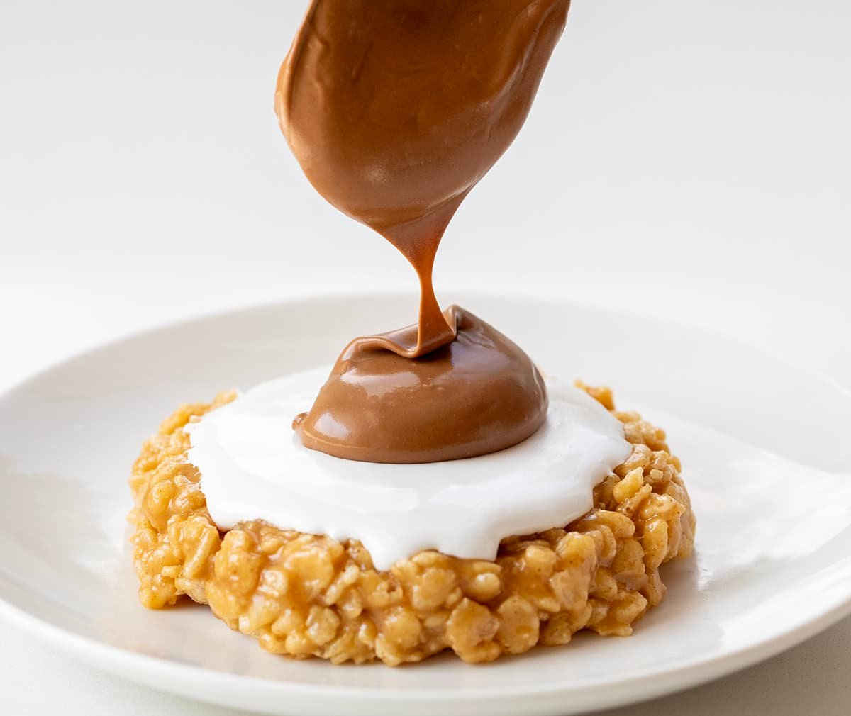 Adding chocolate on top of marshmallow fluff for a S'mores Scotcheroo's.