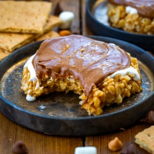 Bitten into S'mores Scotcheroo on a plate on a wooden table.
