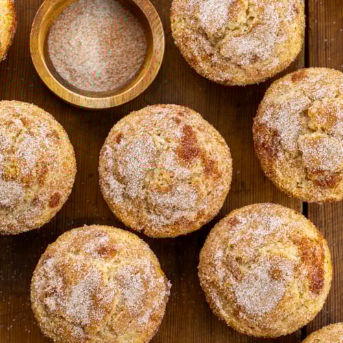 Snickerdoodle Muffins on a wooden table with cinnamon sugar from overhead.