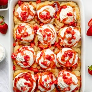 White pan with Strawberry Shortcake Cinnamon Rolls on a white counter from overhead.