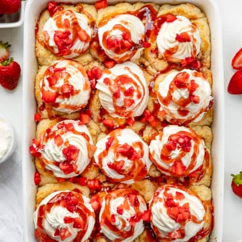 White pan with Strawberry Shortcake Cinnamon Rolls on a white counter from overhead.