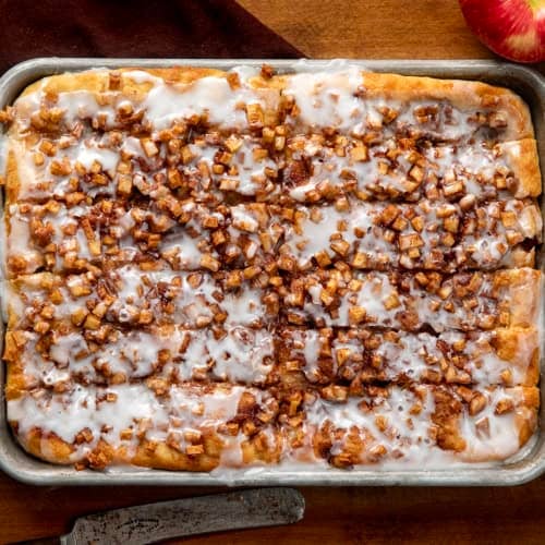 Apple Fritter Focaccia cut into pieces in the pan on a wooden table from overhead.