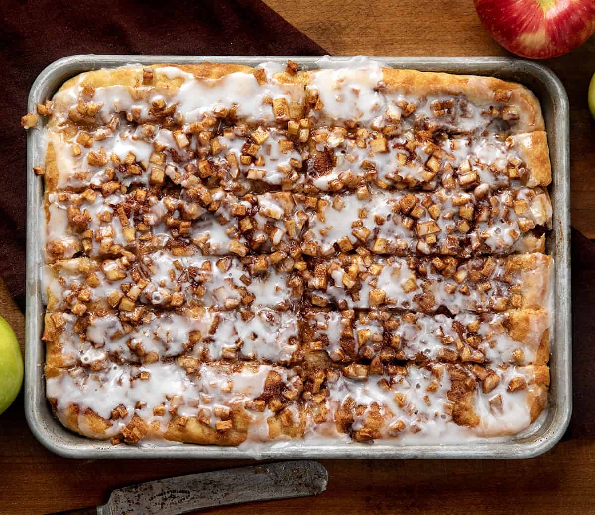 Apple Fritter Focaccia cut into pieces in the pan on a wooden table from overhead.