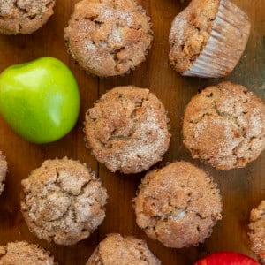 Apple Snickerdoodle Muffins on a wooden table from overhead with fresh apples.