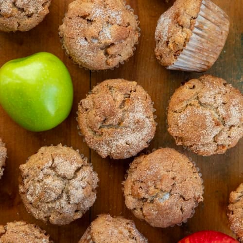 Apple Snickerdoodle Muffins on a wooden table from overhead with fresh apples.