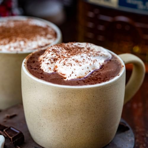 Close up of mugs of Bad Santa Hot Chocolate topped with whipped cream and shaved chocolate.
