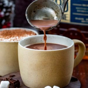 Pouring bourbon hot chocolate into a mug.