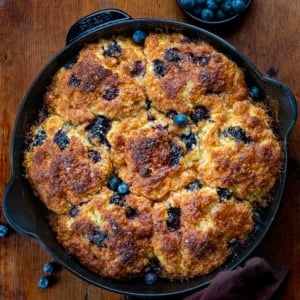 Skillet of Blueberry Cinnamon Crunch Cathead Biscuits on a wooden table from overhead.
