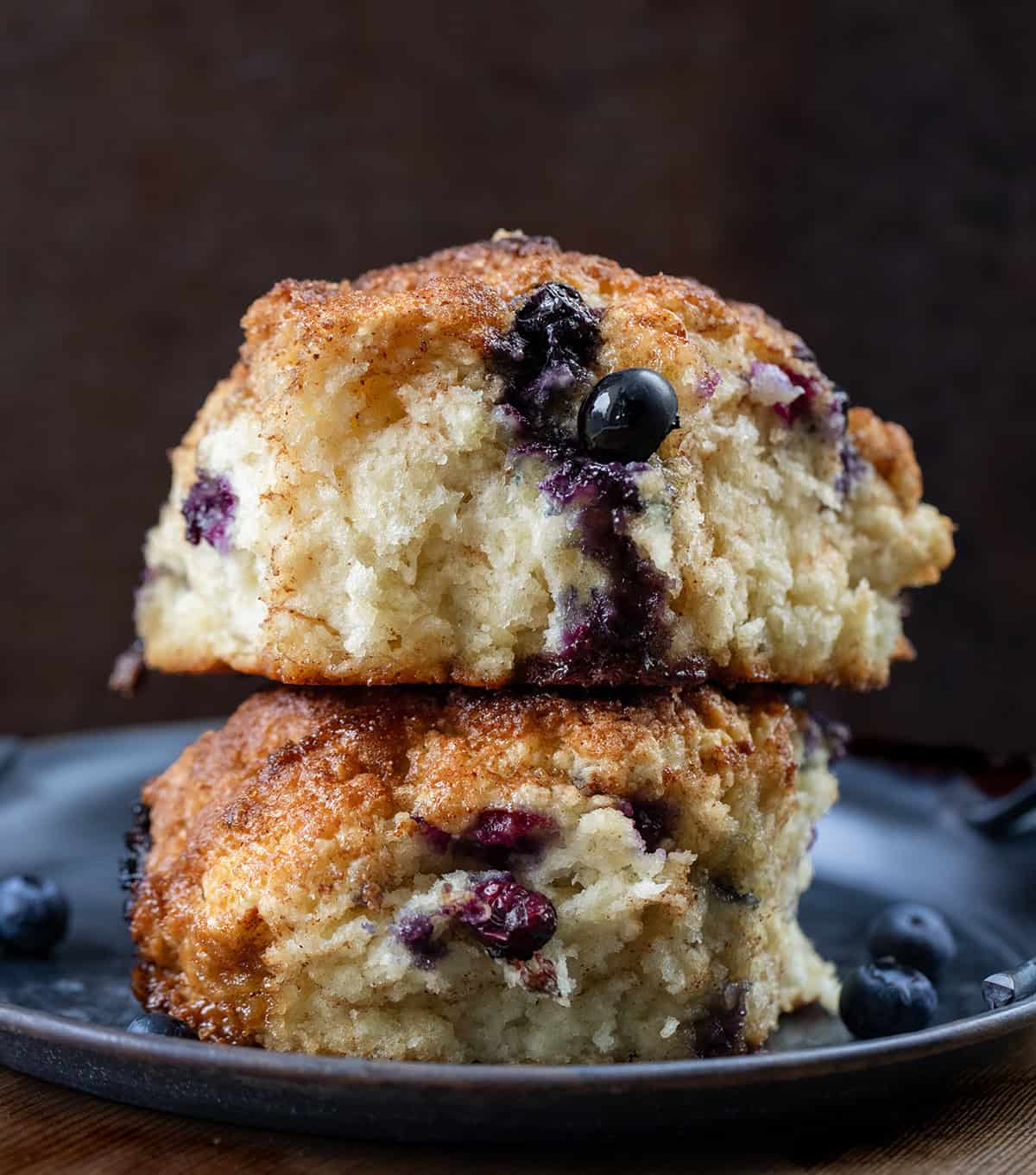 Blueberry Cinnamon Crunch Cathead Biscuits stacked on a black plate very close up.