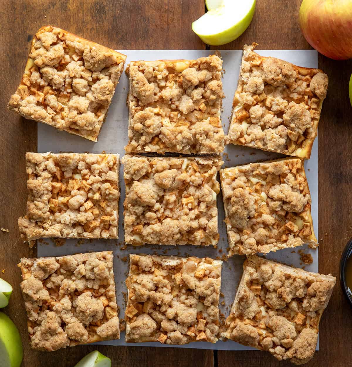 Caramel Apple Cheesecake Bars cut into squares on a wooden table from overhead.