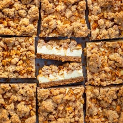 Caramel Apple Cheesecake Bars cut into squares with the center square having bars on their side.
