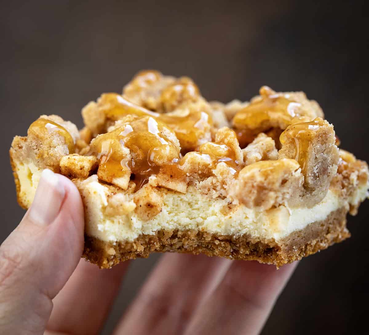 Hand holding a Caramel Apple Cheesecake Bar very close up.