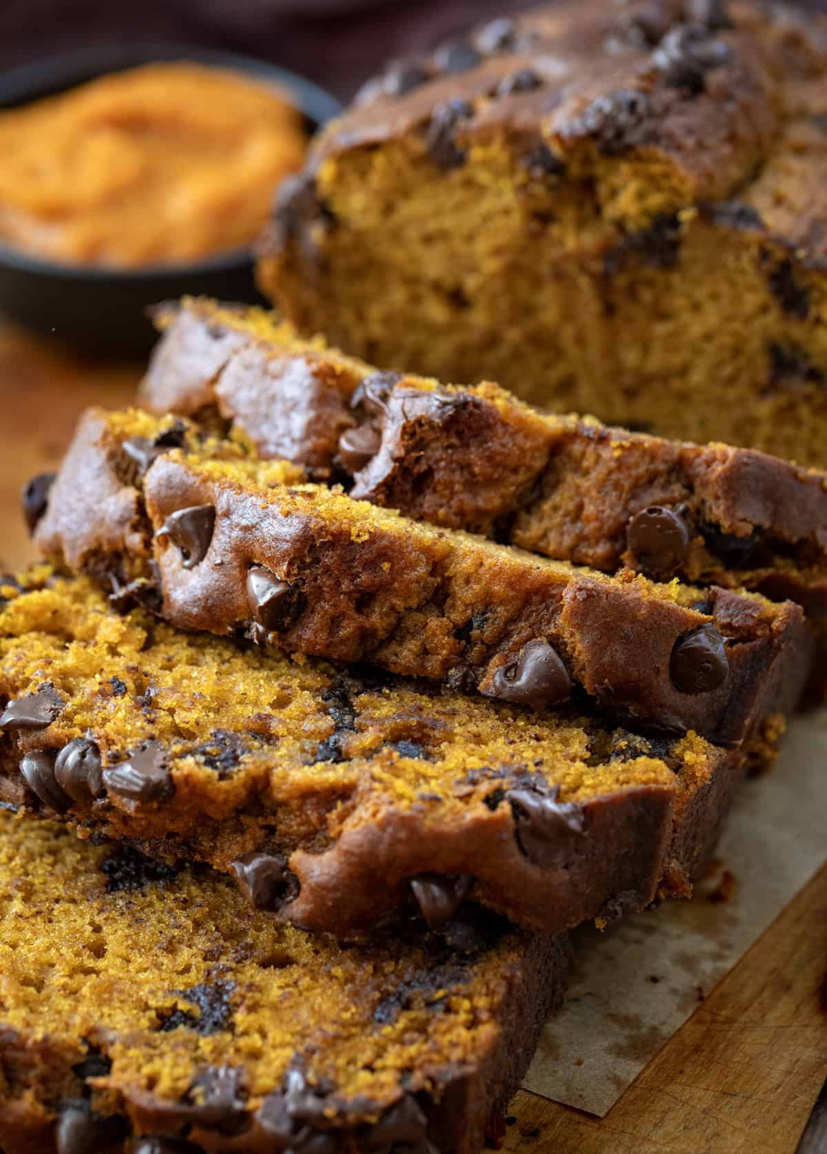 This Chocolate Chip Pumpkin Bread is soft, tender, and loaded with melty chocolate chips inside and on top. Sweet enough to feel like a treat but still full of that cozy pumpkin flavor we all love, itโs the perfect quick bread for fall baking! Close up of slices of Chocolate Chip Pumpkin Bread.