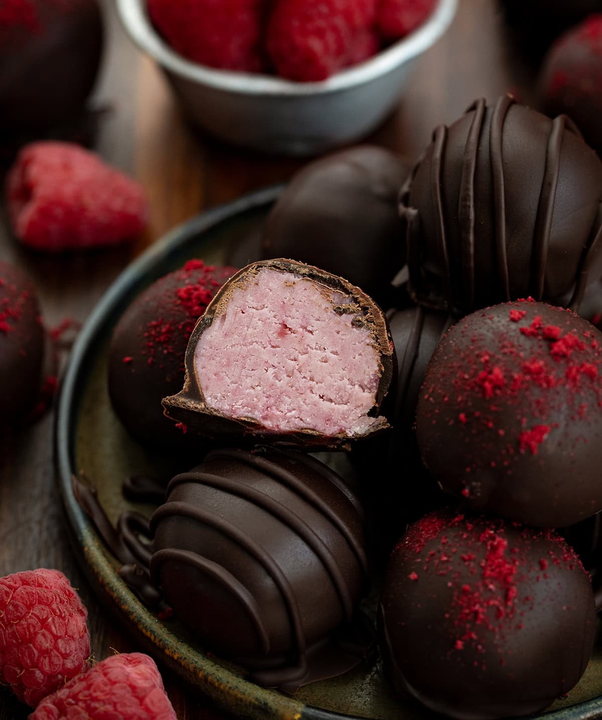 If you love the bold pairing of chocolate and raspberries, these Chocolate Raspberry Truffles are a treat youโll want to make again and again! Chocolate Raspberry Truffles on a plate with top truffle cut in half showing creamy pink texture inside.