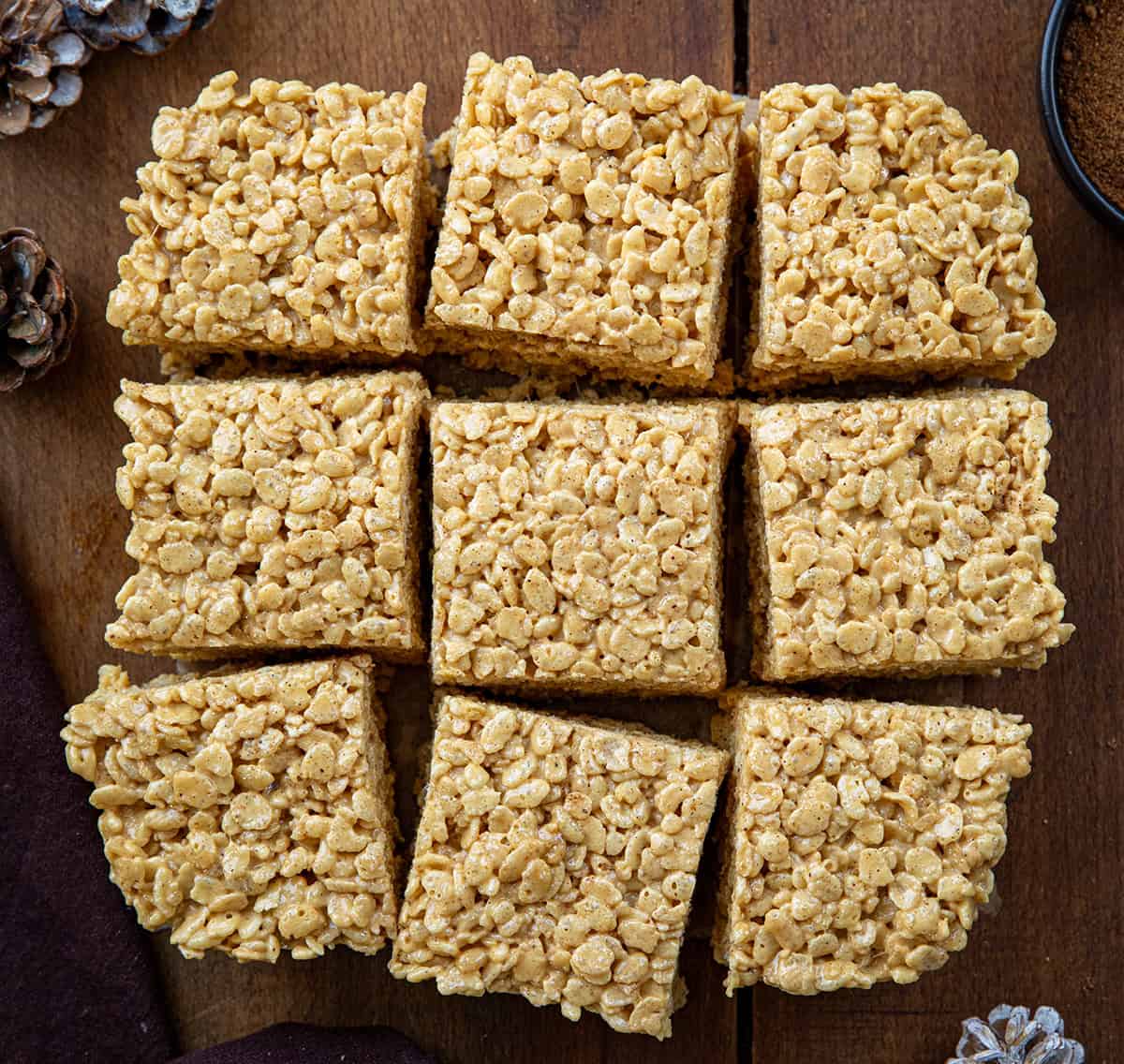 Gingerbread Rice Krispie Treats cut into squares on a wooden table from overhead.