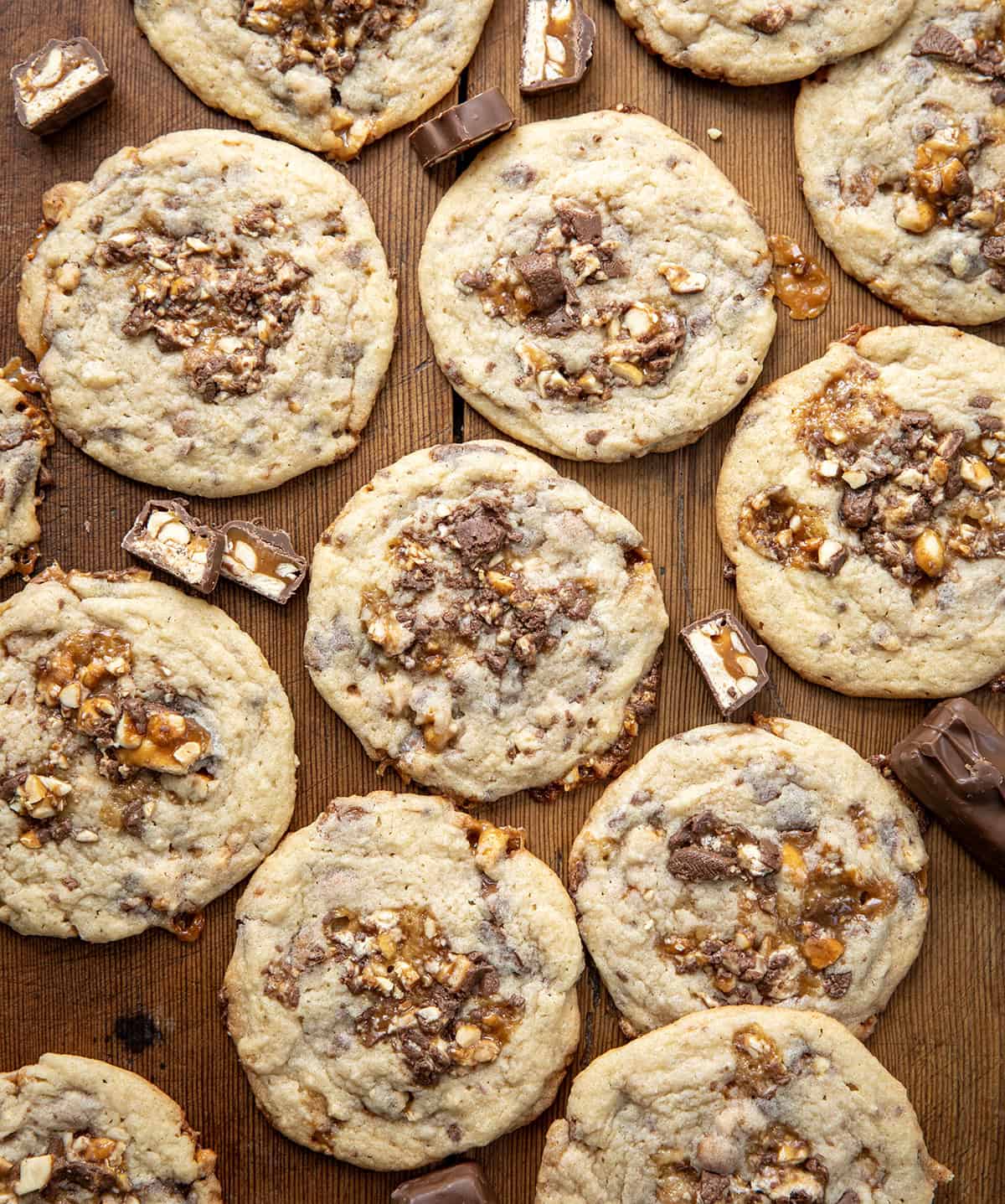 Snickers Cookies on a wooden table from overhead.