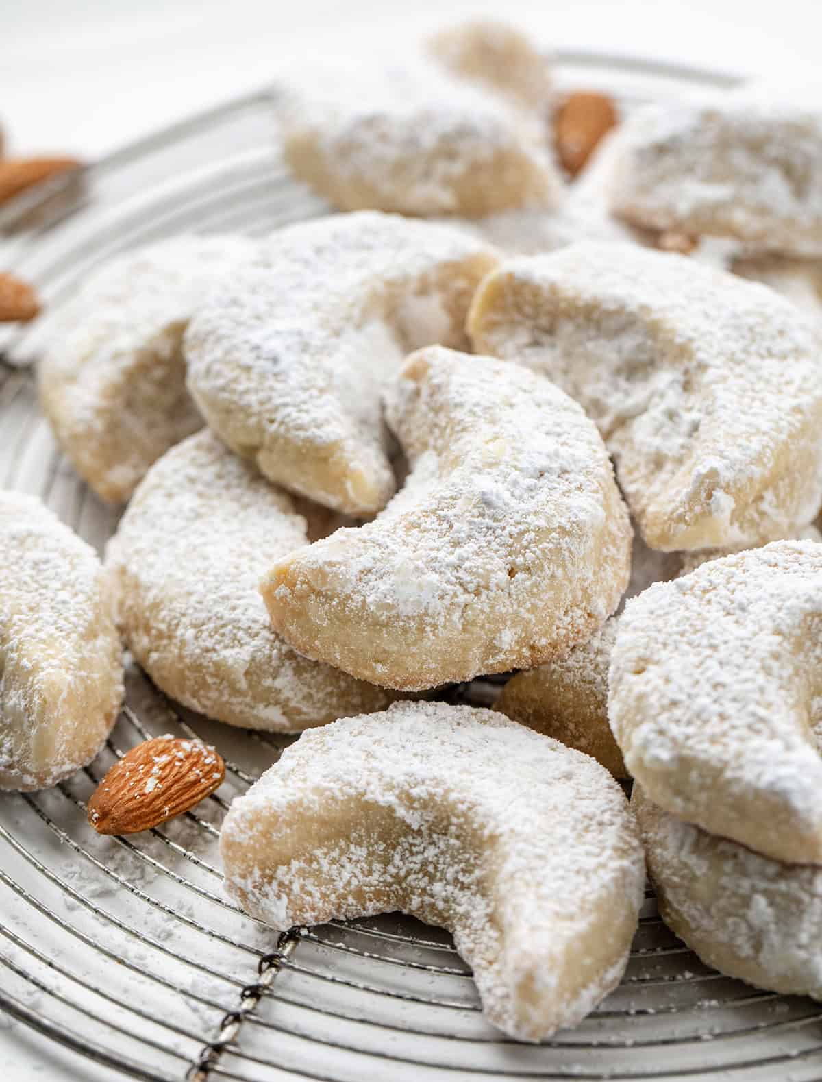 There’s something magical about these delicate almond crescent cookies. They’re buttery, tender, and melt-in-your-mouth soft, with just the right dusting of sweet confectioners’ sugar! Close up of Almond Crescent Cookies on a rack.