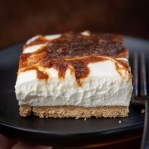 Apple Butter Cheesecake Bar on a black plate with a fork.