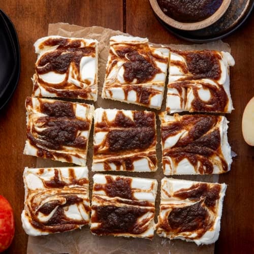 Apple Butter Cheesecake Bars cut into squares on a wooden table from overhead.