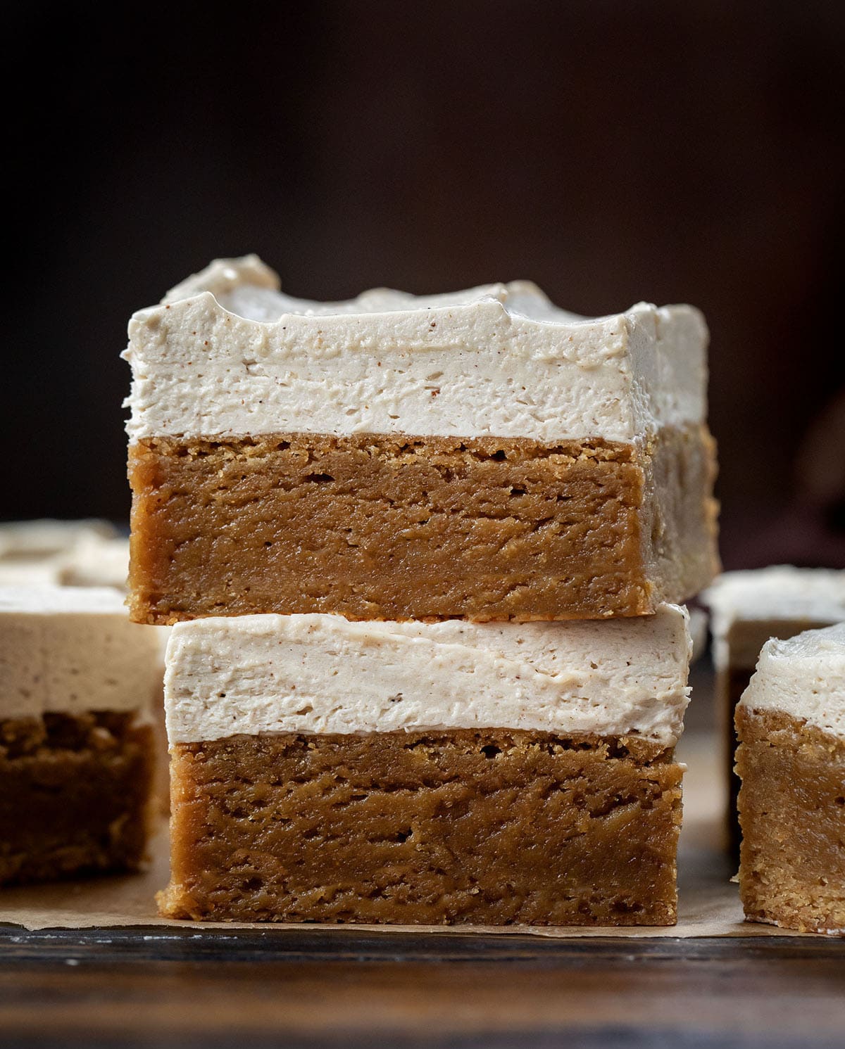 These Frosted Gingerbread Brownies start with my beloved gingerbread brownie base and get a decadent upgrade with a creamy gingerbread ermine frosting. The brownies are soft, tender, and perfectly spiced, while the frosting adds a silky, sweet layer that melts in your mouth! Frosted Gingerbread Brownies stacked on a wooden table.