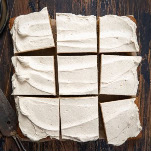 Frosted Gingerbread Brownies cut into squares on a wooden table from overhead.
