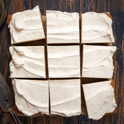 Frosted Gingerbread Brownies cut into squares on a wooden table from overhead.