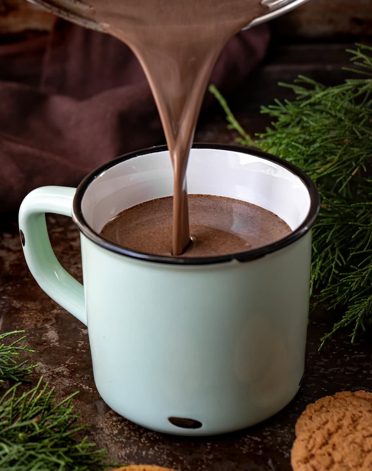 Pouring Gingerbread Hot Chocolate into a mug on a dark table.