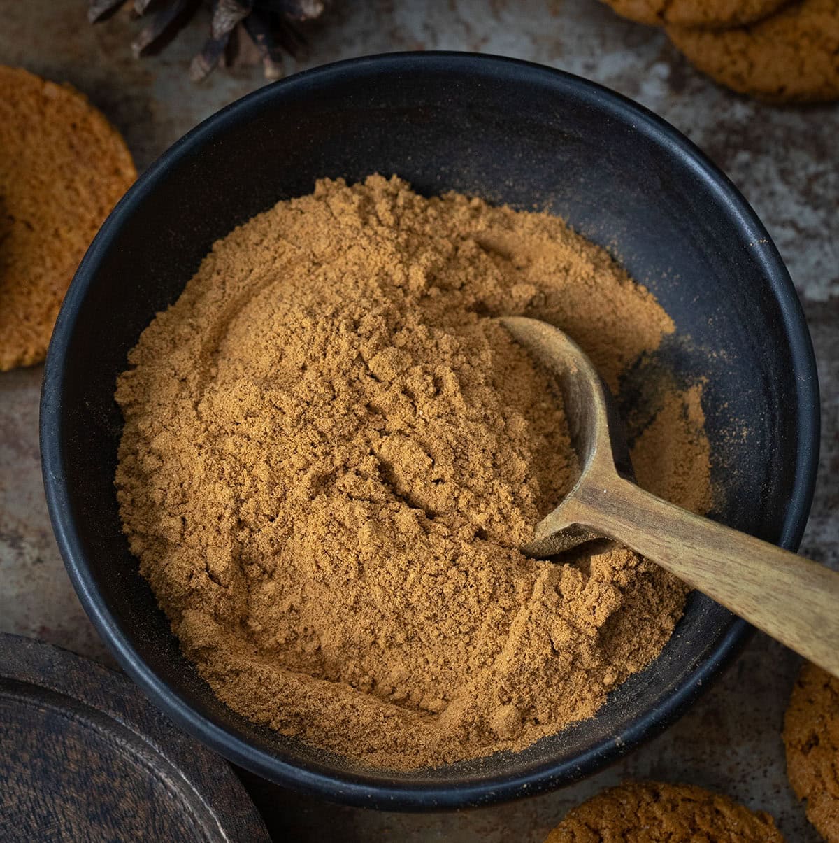 Warm up your winter baking with my special Gingerbread Spice Mix! A cozy, homemade blend that instantly makes your kitchen smell like the holidays. This easy mix captures all the nostalgic flavor of classic gingerbread in one jar! Black bowl of Gingerbread Spice Mix with a measuring spoon in the mix.